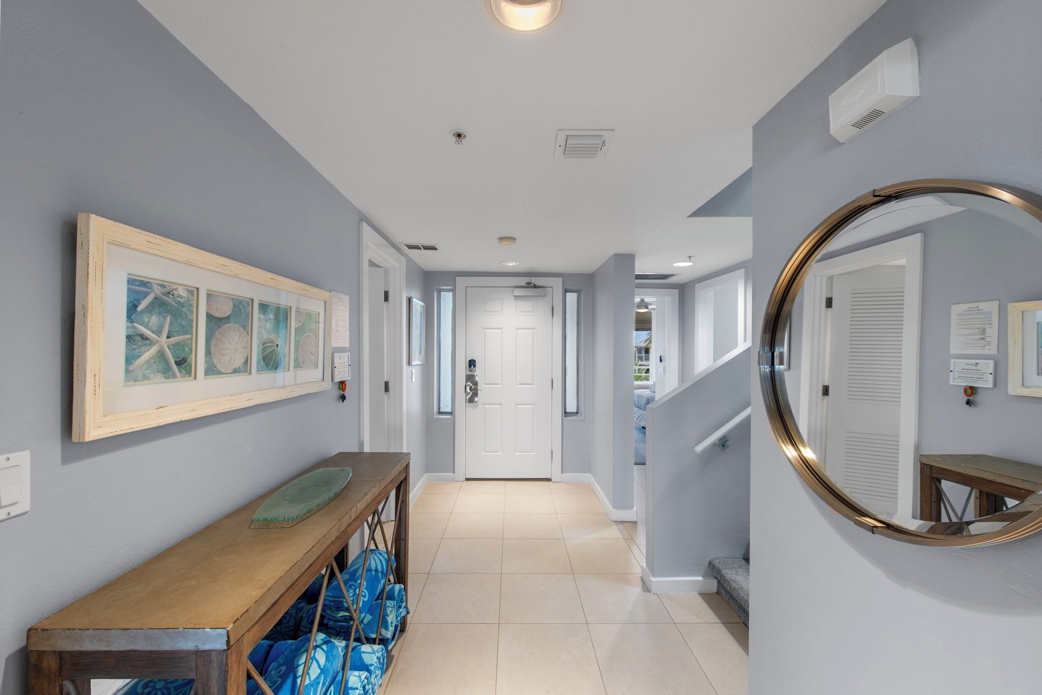 Un couloir avec un banc en bois, un tableau encadré et un miroir au mur.
