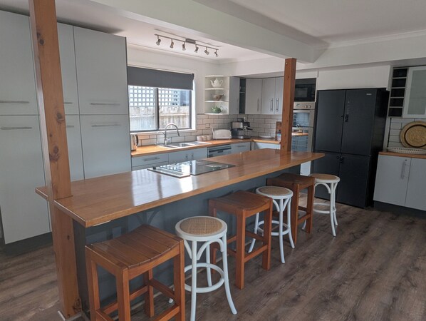 A kitchen with a wooden island, bar stools, and a refrigerator.