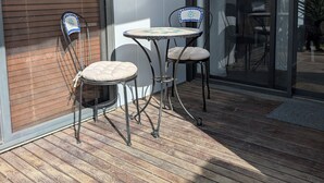Un patio con dos mesas y sillas, un gran ventanal corredero y una terraza de madera.