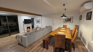 Una sala de estar moderna con chimenea, una mesa de comedor con sillas, un sofá y un televisor.