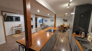 Una cocina moderna con una isla de madera, electrodomésticos integrados y una zona de comedor con vistas al salón.