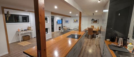 A modern kitchen with a wooden island, built-in appliances, and a dining area with a view of the living room.