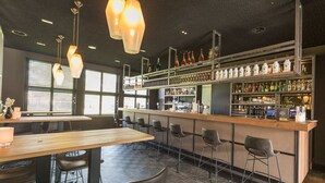Un espace bar doté d’un long comptoir, de nombreux tabourets et d’une variété de bouteilles exposées sur des étagères.