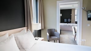 A hotel room with a bed, a chair, a desk, a TV, and a view into a dining area. - A Serene Dutch Getaway with Monastic Charm and Natural Surroundings! (Deurne)