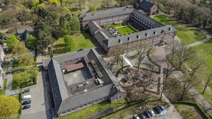 An aerial view of a large campus with multiple buildings, a central courtyard, and surrounding green areas. - Stay in the Heart of Nature With Comfort All Around! Onsite Dining, Free Parking (Deurne)