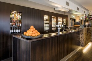 A bar area with a central island, shelves of liquor bottles, and a decorative arrangement of oranges. - Escape to Nature | Scenic Hotel Room with Views of the Dutch Forest! (Berg en Dal)