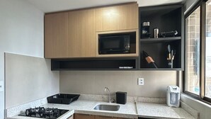 Una cucina compatta con fornello a gas, forno a microonde, lavandino e frigorifero.