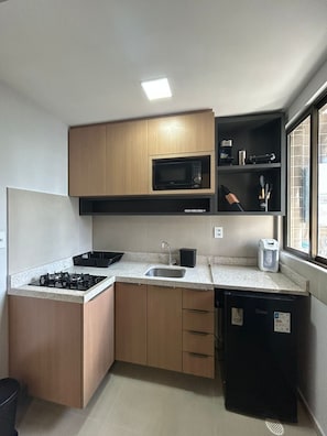 A compact kitchen with a gas stove, a microwave, a sink, and a refrigerator.