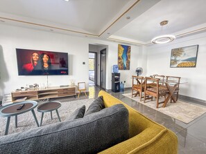 Ein modernes Wohnzimmer mit Flachbildfernseher, einem Holzessttisch und einer Couch.