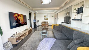 A modern living room with a flat-screen TV, a sofa, a coffee table, and a dining area with chairs. - Welcoming 2-bedroom apartment with fitness room in Nairobi (Nairobi)