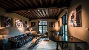 A cozy room with a leather sofa, wooden beams, and artwork on the walls.