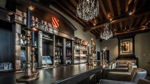 A bar area with a wooden bar counter, shelves of liquor bottles, and a mounted animal head on the wall.