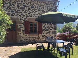A stone building with a patio, a table with chairs, and an umbrella.