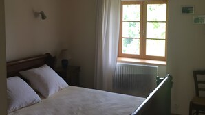 A bedroom with a bed, a window with curtains, a radiator, and a chair. - “Gîte Les Bannes” with Mountain View and Wi-Fi (Saint-Sauves-d'Auvergne)