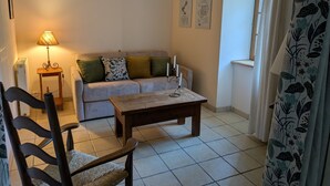 A living room with a sofa, a wooden coffee table, a lamp, and a chair. - “Gîte Les Bannes” with Mountain View and Wi-Fi (Saint-Sauves-d'Auvergne)