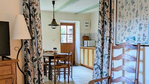 A room with a wooden cabinet, a chair, a table, a television, and a kitchen area in the background. - “Gîte Les Bannes” with Mountain View and Wi-Fi (Saint-Sauves-d'Auvergne)