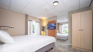 A hotel room with a large bed, a wardrobe, a television, and a view of the outside. - Comfortable Room – Perfect for Family Getaway in Dwingeloo! Free Parking! (Dwingeloo)