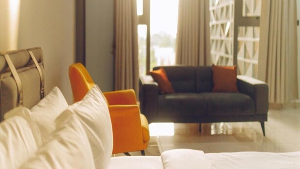 Quarto de hotel com cama, sofá e poltrona.