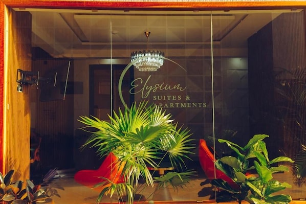 A hotel entrance with a sign reading 'Elysium Suites & Apartments,' a chandelier, and indoor plants. - Elysium Suites & Apartments (Pantang West)