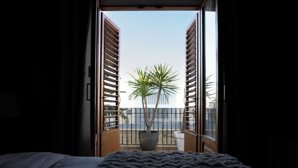 A bedroom with a bed, a view of a balcony with a potted plant, and a clear sky. - Peaceful 3-bedroom apartment with AC in El Puig de Santa Maria (El Puig de Santa Maria)