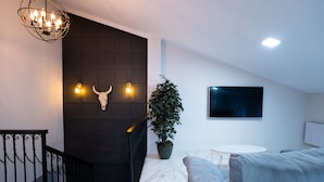 A modern living room with a staircase, a potted plant, a flat-screen TV, and a marble floor. - Peaceful 3-bedroom apartment with AC in El Puig de Santa Maria (El Puig de Santa Maria)