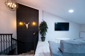 Een moderne woonkamer met een trap, een potplant, een flatscreentelevisie en een marmeren vloer.