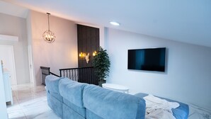 A modern living room with a sectional sofa, a flat-screen TV, a chandelier, and a potted plant. - Peaceful 3-bedroom apartment with AC in El Puig de Santa Maria (El Puig de Santa Maria)