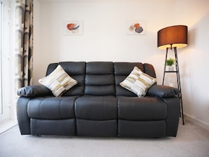 A black leather sofa with two decorative pillows, a floor lamp, and two wall art pieces. - Spacious 4BR Contractor Family Home Parking (Calne)