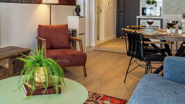 A modern living room with a red armchair, a round table with a plant, and a dining area with a table set for two. - 5min to Taksim, Bosphorus View & Terrace (Istanbul)