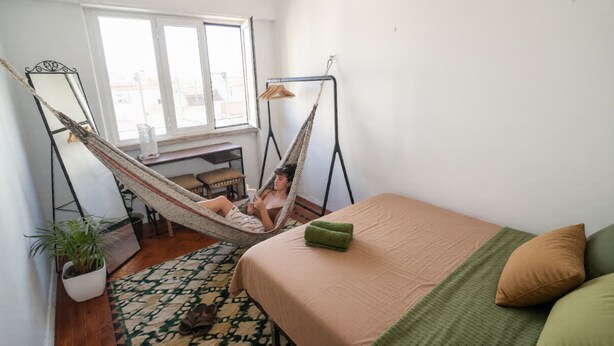 A room with a bed, a hammock, a desk, and a window. - Maria (Lisbon)