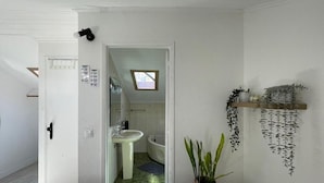 A bathroom with a sink, mirror, and a potted plant. - Maria (Lisbon)