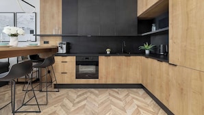 Une cuisine moderne avec des meubles en bois, un plan de travail noir et un sol à motifs en chevrons.