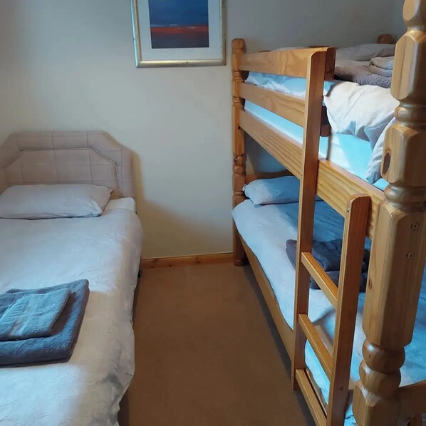 A room with bunk beds, a framed picture on the wall, and a carpeted floor.