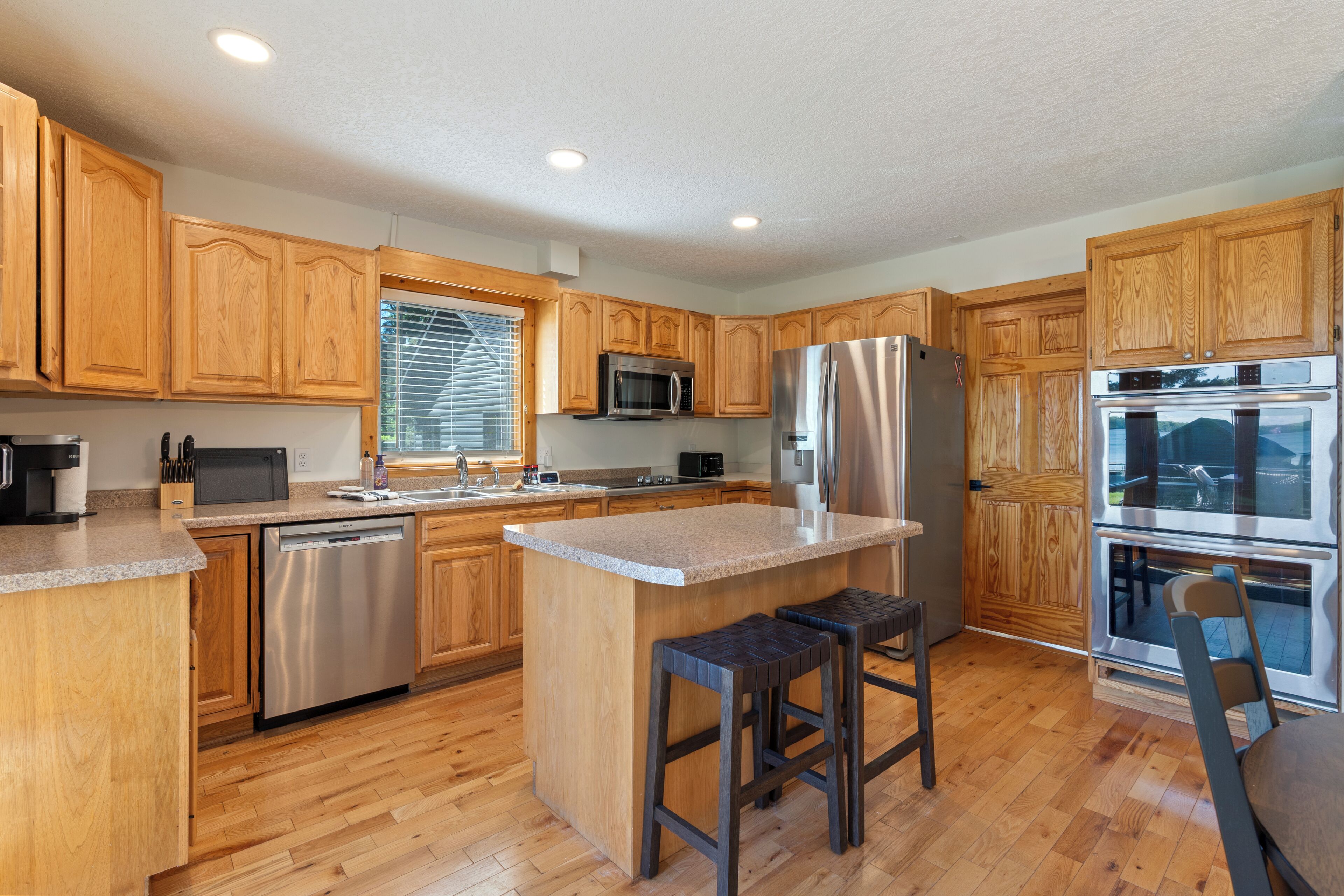 A modern kitchen with wooden cabinets, stainless steel appliances, and a granite countertop.