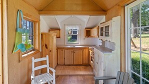 A wooden interior with a kitchen area, a window, and a door.