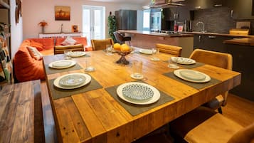 A modern dining area with a wooden table set for six, surrounded by leather chairs.