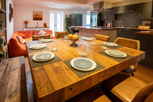 A modern dining area with a wooden table set for six, surrounded by leather chairs.
