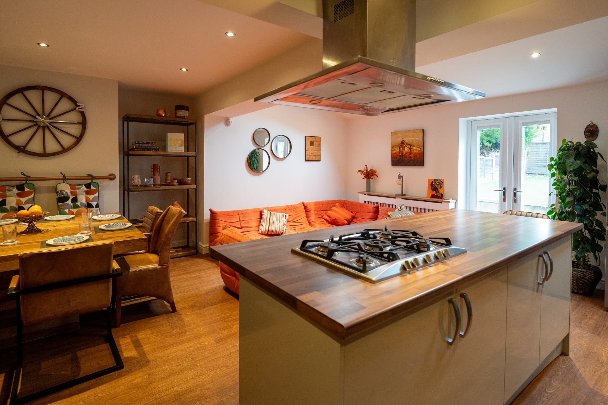 A modern kitchen with a central island, a dining area with a wooden table, and a cozy seating area with a sofa.