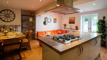 A modern kitchen with a central island, a dining area with a wooden table, and a cozy seating area with a sofa.
