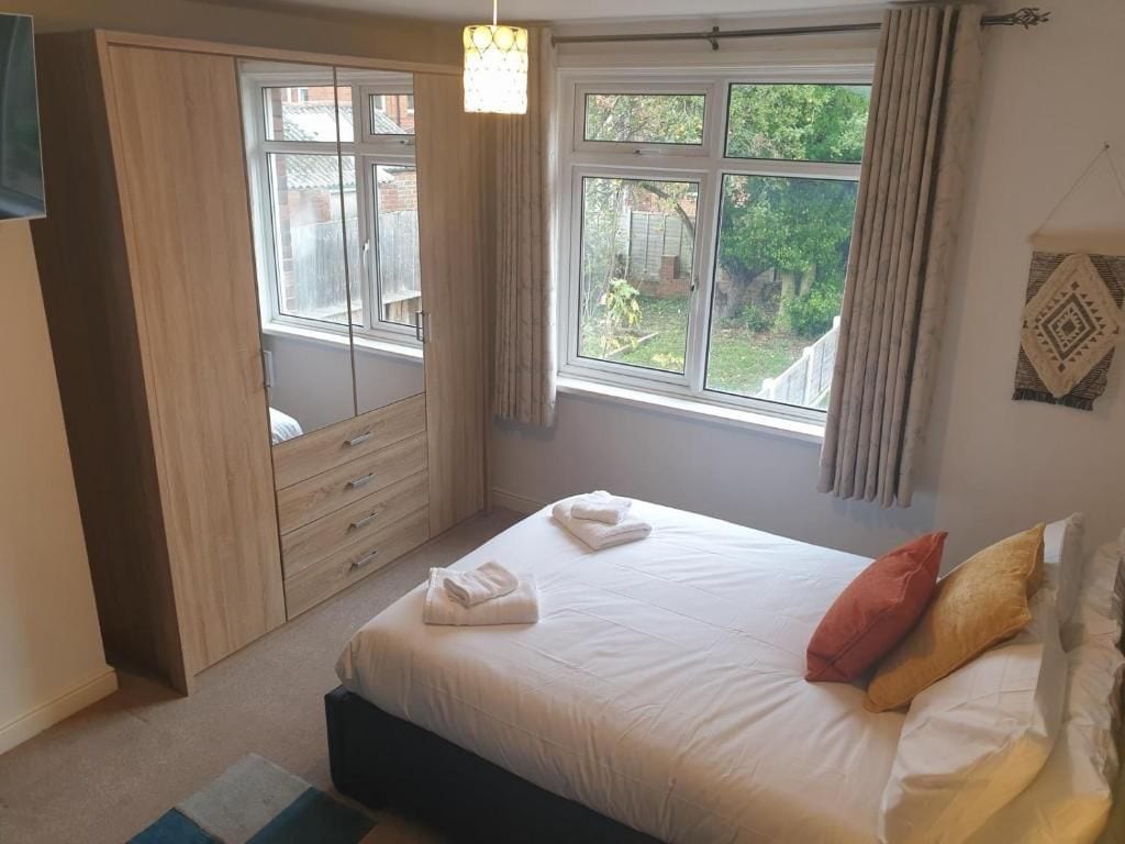 A bedroom with a bed, a wardrobe, and a window with curtains.