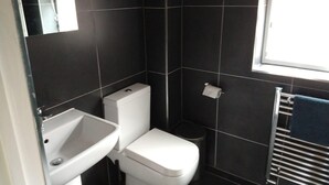 Een kleine, moderne badkamer met toilet, wastafel en handdoekrek.