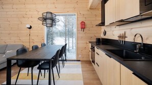 A modern kitchen with wooden walls, a dining area with a table and chairs, and a large window. - Porevillas Iso-Syöte A (Syöte)
