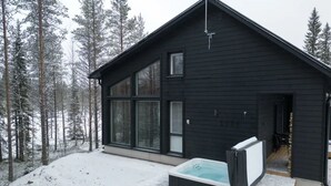 A modern black cabin with large windows, a hot tub, and a wooden deck. - Porevillas Iso-Syöte A (Syöte)