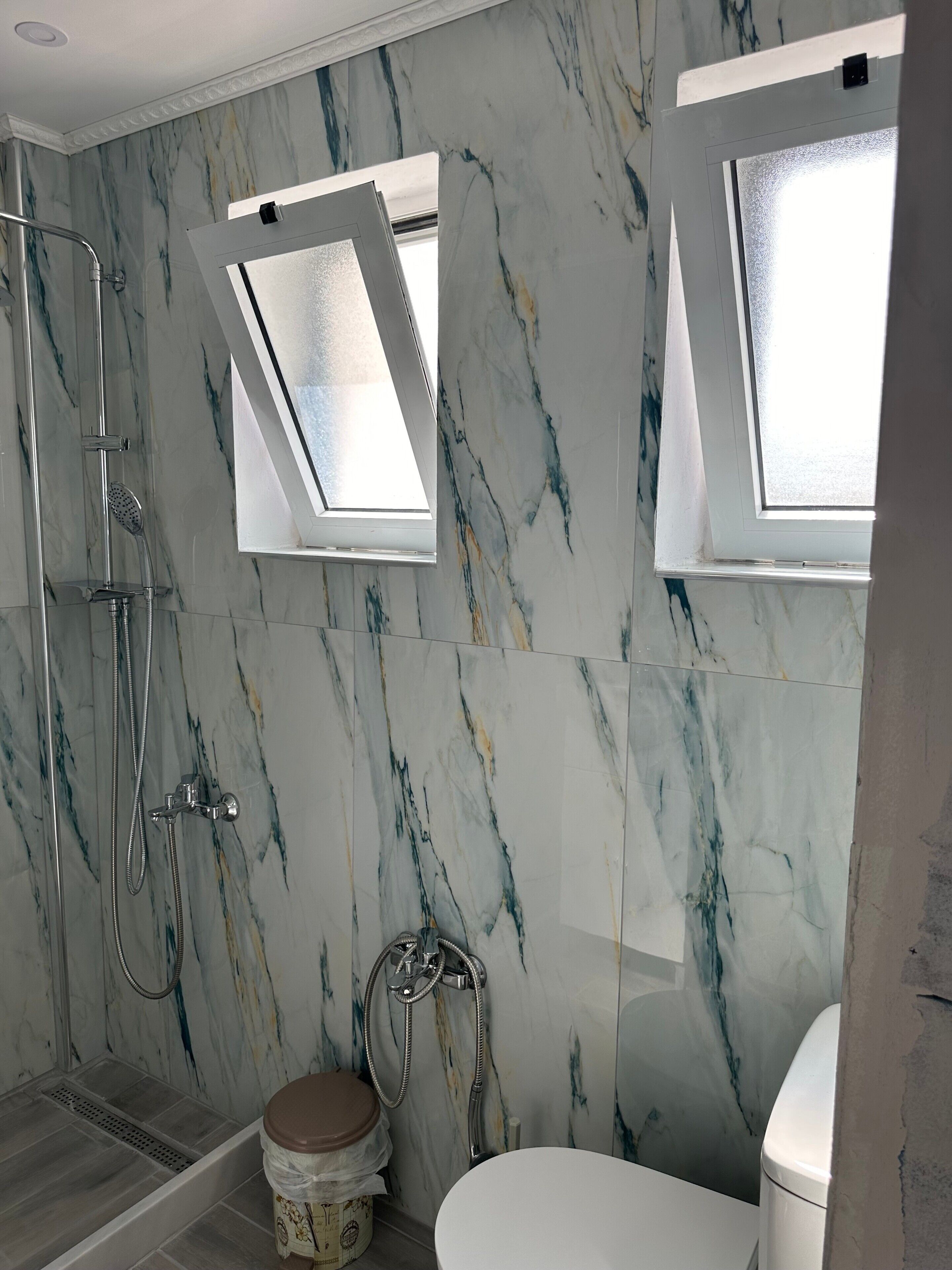 Une salle de bain avec douche, toilettes et fenêtres de toit.