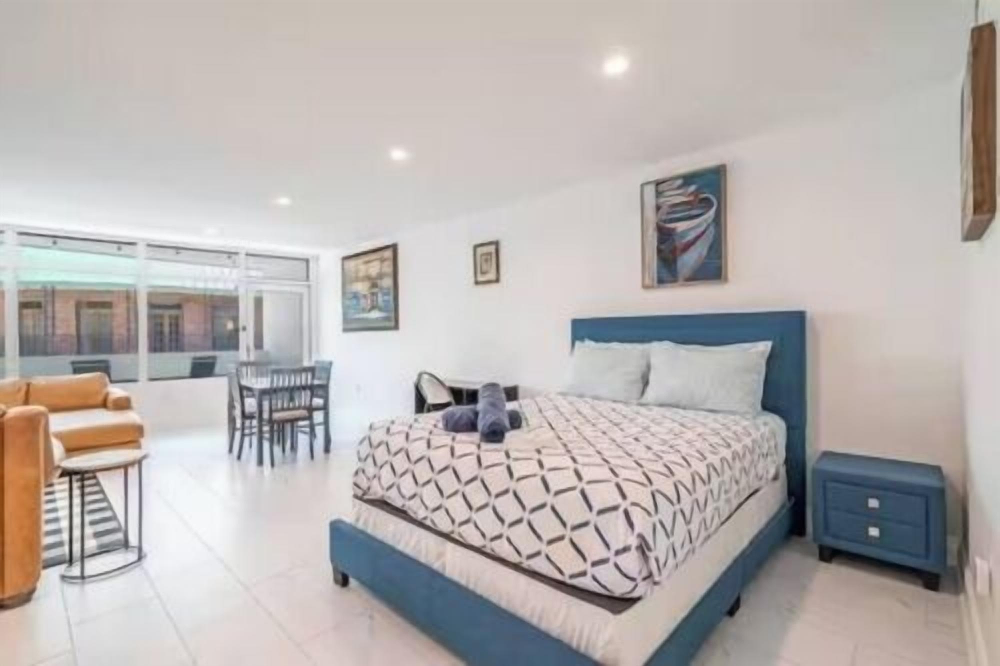 Une chambre à coucher avec un lit, une table de chevet, une chaise, un bureau et une fenêtre.