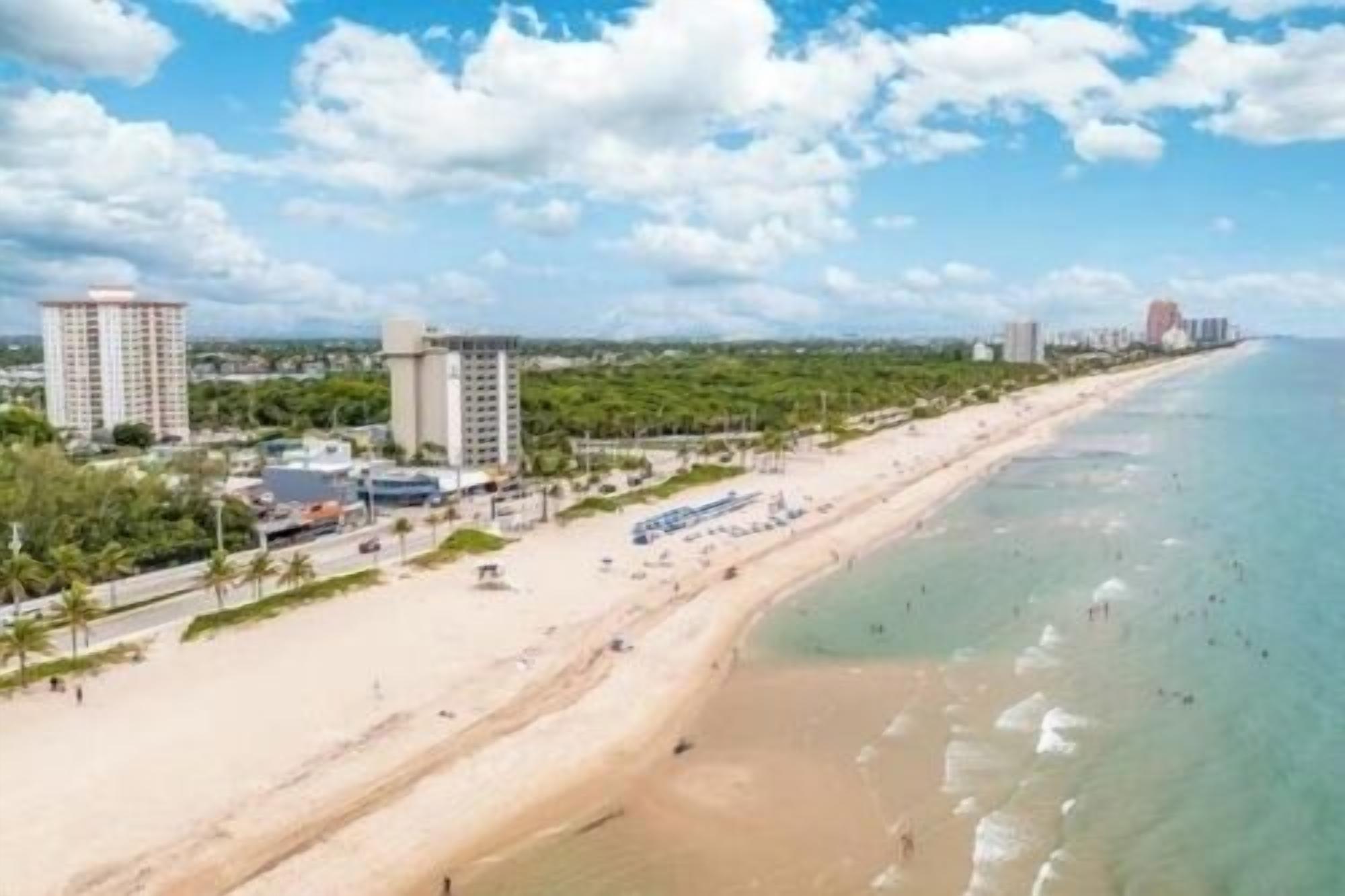 A coastal hotel with a beach view, multiple buildings, and a clear sky.