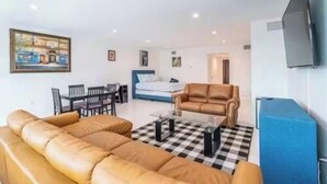 Ein Wohnzimmer mit einer Couch, einem Couchtisch, einem Fernseher und einem Bett im Hintergrund.