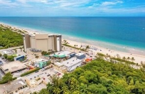 Ein Hotel an der Küste mit Blick auf den Strand, mehreren Gebäuden und wolkenlosem Himmel.