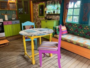 Ein farbenfroher Raum mit einem runden Tisch, einem violetten Stuhl und einem gemusterten Sofa.