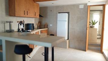 Una cocina moderna con armarios de madera, un refrigerador blanco, un lavamanos y un comedor con mesa y sillas.